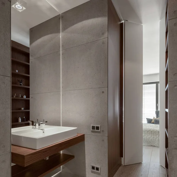 Stylish bathroom with decorative concrete tiles on the walls, wooden floor, shelves and wall