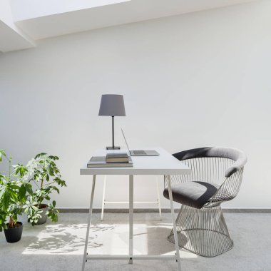 Beyaz duvarlı ve gri halılı tavan arasında çalışmak ya da çalışmak için basit bir ofis alanı.