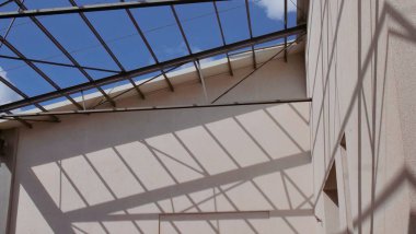 Mavi gökdelen geometrisi, endüstriyel tasarım, ışık ve gölge desenli çelik çatı yapısından alçı duvarın üzerindeki modern mimari gölgeler kentsel mimari arka planlar için mükemmeldir..