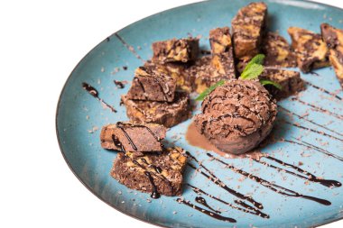 İştah açıcı ile fındık ve bir dondurma çikolatalı kek parçaları mavi tabak içinde yalan bir dökme sos ile top ve beyaz bir arka plan üzerinde izole