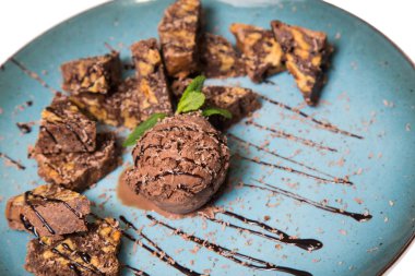 İştah açıcı ile fındık ve bir dondurma çikolatalı kek parçaları mavi tabak içinde yalan bir dökme sos ile top ve beyaz bir arka plan üzerinde izole