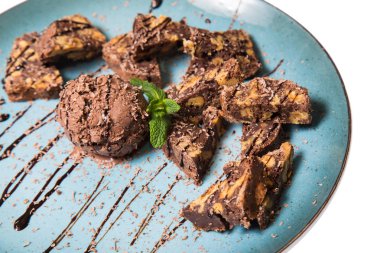 İştah açıcı ile fındık ve bir dondurma çikolatalı kek parçaları mavi tabak içinde yalan bir dökme sos ile top ve beyaz bir arka plan üzerinde izole