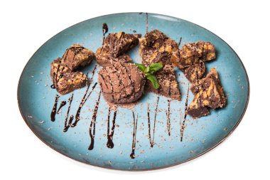 İştah açıcı ile fındık ve bir dondurma çikolatalı kek parçaları mavi tabak içinde yalan bir dökme sos ile top ve beyaz bir arka plan üzerinde izole