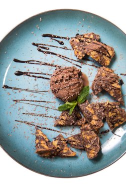 İştah açıcı ile fındık ve bir dondurma çikolatalı kek parçaları mavi tabak içinde yalan bir dökme sos ile top ve beyaz bir arka plan üzerinde izole