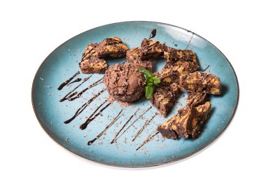 İştah açıcı ile fındık ve bir dondurma çikolatalı kek parçaları mavi tabak içinde yalan bir dökme sos ile top ve beyaz bir arka plan üzerinde izole