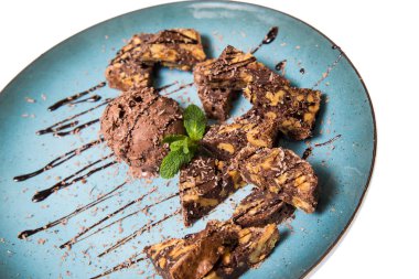 İştah açıcı ile fındık ve bir dondurma çikolatalı kek parçaları mavi tabak içinde yalan bir dökme sos ile top ve beyaz bir arka plan üzerinde izole