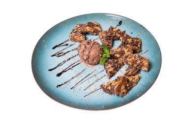 İştah açıcı ile fındık ve bir dondurma çikolatalı kek parçaları mavi tabak içinde yalan bir dökme sos ile top ve beyaz bir arka plan üzerinde izole