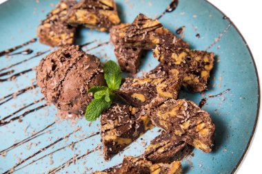 İştah açıcı ile fındık ve bir dondurma çikolatalı kek parçaları mavi tabak içinde yalan bir dökme sos ile top ve beyaz bir arka plan üzerinde izole