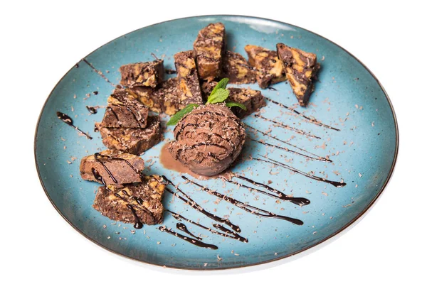 İştah açıcı ile fındık ve bir dondurma çikolatalı kek parçaları mavi tabak içinde yalan bir dökme sos ile top ve beyaz bir arka plan üzerinde izole