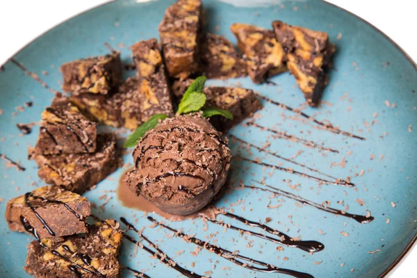 İştah açıcı ile fındık ve bir dondurma çikolatalı kek parçaları mavi tabak içinde yalan bir dökme sos ile top ve beyaz bir arka plan üzerinde izole