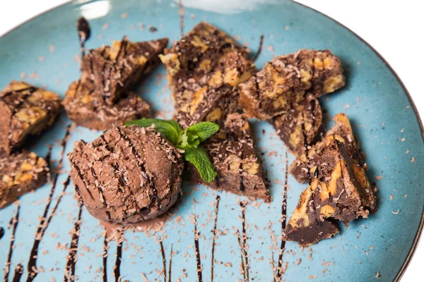 İştah açıcı ile fındık ve bir dondurma çikolatalı kek parçaları mavi tabak içinde yalan bir dökme sos ile top ve beyaz bir arka plan üzerinde izole