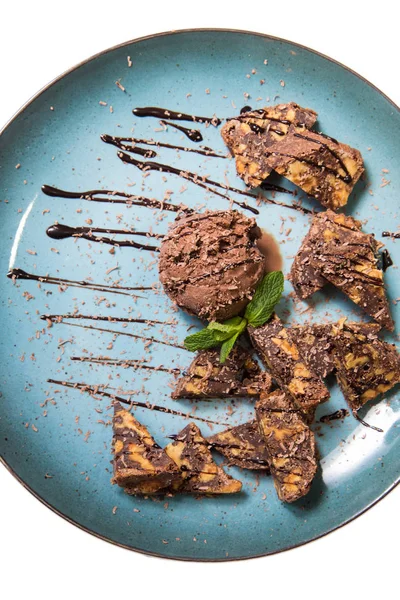 İştah açıcı ile fındık ve bir dondurma çikolatalı kek parçaları mavi tabak içinde yalan bir dökme sos ile top ve beyaz bir arka plan üzerinde izole