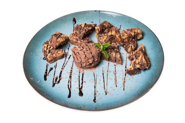 İştah açıcı ile fındık ve bir dondurma çikolatalı kek parçaları mavi tabak içinde yalan bir dökme sos ile top ve beyaz bir arka plan üzerinde izole