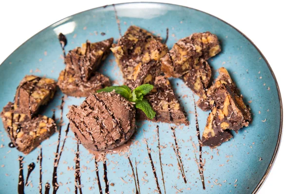 İştah açıcı ile fındık ve bir dondurma çikolatalı kek parçaları mavi tabak içinde yalan bir dökme sos ile top ve beyaz bir arka plan üzerinde izole