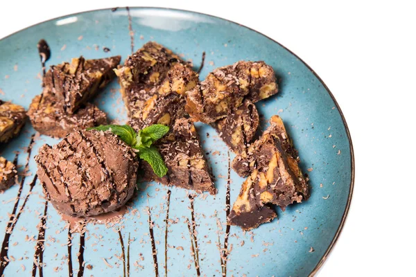 İştah açıcı ile fındık ve bir dondurma çikolatalı kek parçaları mavi tabak içinde yalan bir dökme sos ile top ve beyaz bir arka plan üzerinde izole