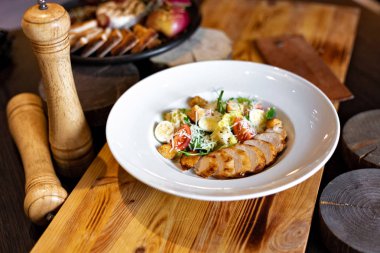 Izgara tavuk, sarımsak croutons, parmesan ve yumurta salatası Romain rustik tarzı ahşap arka plan üzerinde beyaz bir tabakta servis. Restoran hizmet