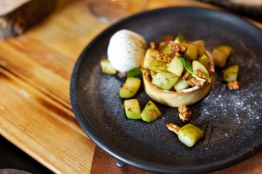 İngilizce elmalı kek ile fındık, nane ve kepçe dondurma rustik tarzı ahşap arka plan üzerinde siyah bir tabakta servis. Restoran hizmet