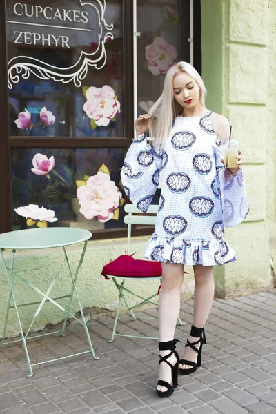 Güzel sarışın suyu ile sokakta yürür