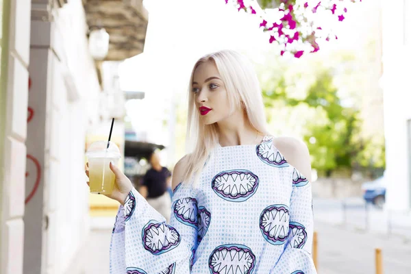 Güzel sarışın suyu ile sokakta yürür