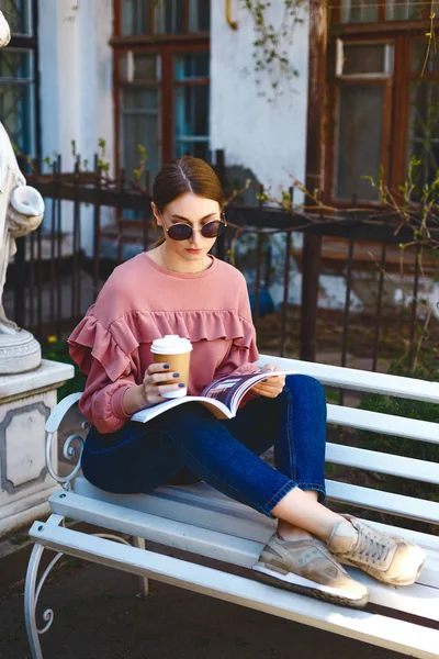 Chica con café y revista en el banco — Foto de Stock