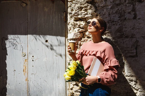 女の子はコーヒーを飲みながら都会の壁の近くに立っている — ストック写真