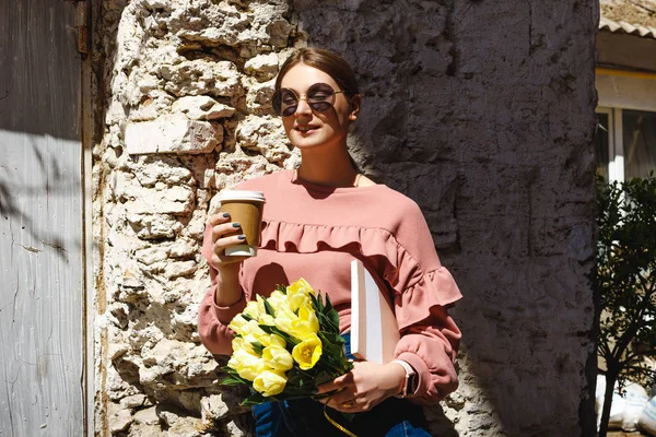 Una chica se para cerca de la pared urbana con una taza de café — Foto de Stock