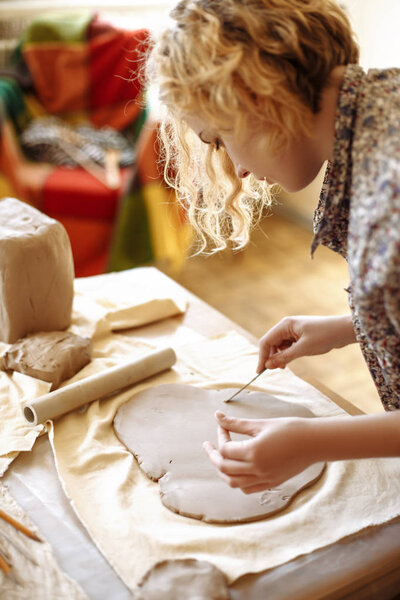 young girl is cutting clay