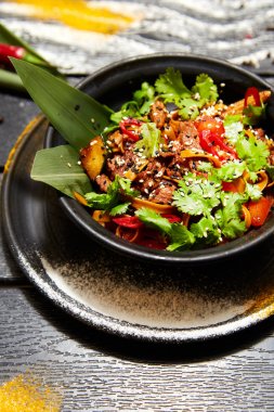 Siyah bir tabakta Asya yemeği. Sığır eti ile Erişte