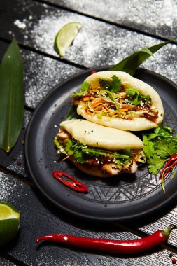 Siyah bir tabakta Asya yemeği. Et ve sebze ile Bao