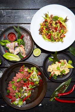 Siyah bir masada Asya yemekleri. Salatalar ve atıştırmalıklar