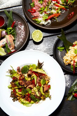 Siyah bir masada Asya yemekleri. Salatalar ve atıştırmalıklar