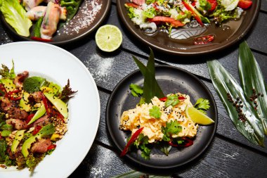 Siyah bir masada Asya yemekleri. Salatalar ve atıştırmalıklar