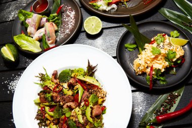 Siyah bir masada Asya yemekleri. Salatalar ve atıştırmalıklar