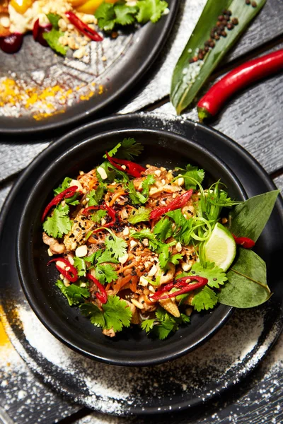 Siyah bir tabakta Asya yemeği. Tavuk ve karides ile Pad Tay