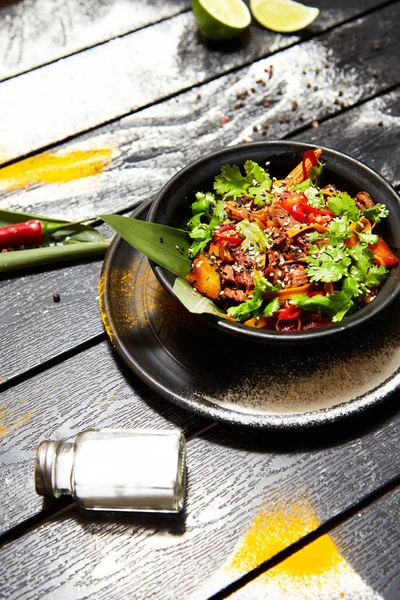 Siyah bir tabakta Asya yemeği. Sığır eti ile Erişte