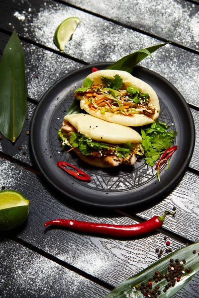 Siyah bir tabakta Asya yemeği. Et ve sebze ile Bao