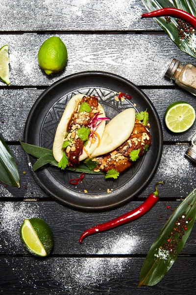 Siyah bir tabakta Asya yemeği. Et ve sebze ile Bao