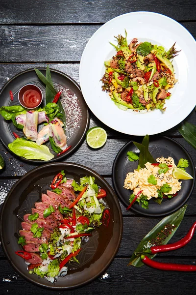 Siyah bir masada Asya yemekleri. Salatalar ve atıştırmalıklar