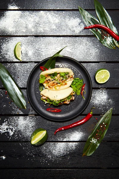 Siyah bir tabakta Asya yemeği. Et ve sebze ile Bao