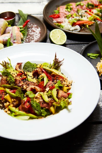 Siyah bir masada Asya yemekleri. Salatalar ve atıştırmalıklar