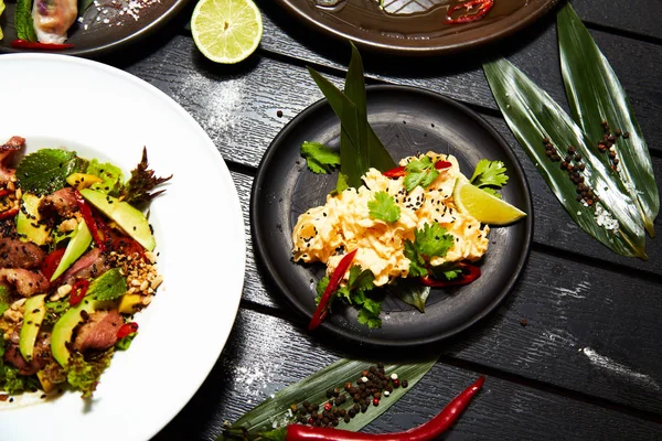 Siyah bir masada Asya yemekleri. Salatalar ve atıştırmalıklar