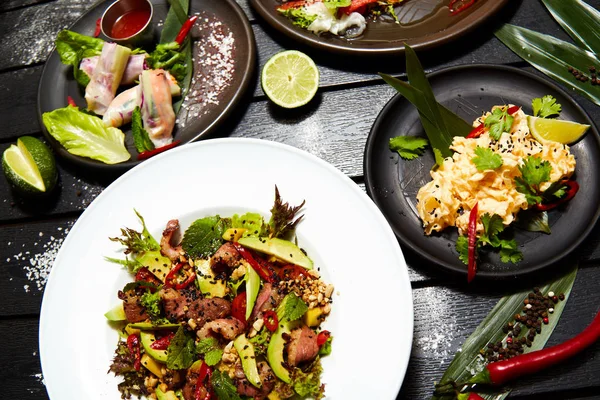 Siyah bir masada Asya yemekleri. Salatalar ve atıştırmalıklar