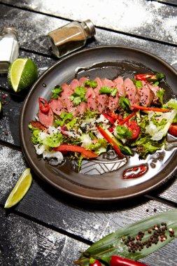 Siyah bir tabakta Asya yemeği. Dana salatası