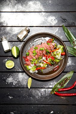 Siyah bir tabakta Asya yemeği. Dana salatası