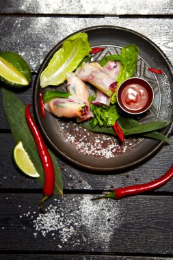 Siyah bir tabakta Asya yemeği. Karides ve soslu bahar rulosu