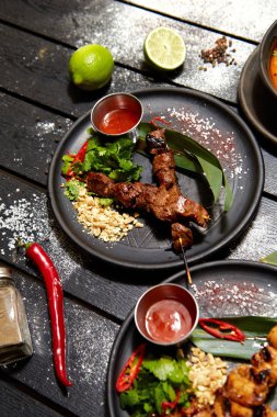 Siyah bir tabakta Asya yemeği. Dana Satay