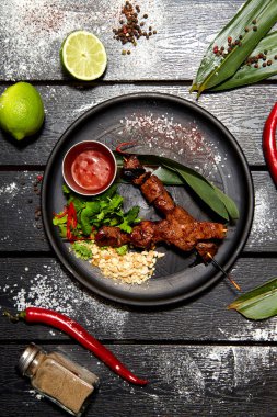 Siyah bir tabakta Asya yemeği. Dana Satay