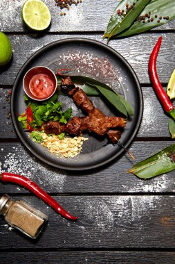 Siyah bir tabakta Asya yemeği. Dana Satay