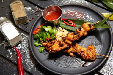 Siyah bir tabakta Asya yemeği. Tavuk Satay