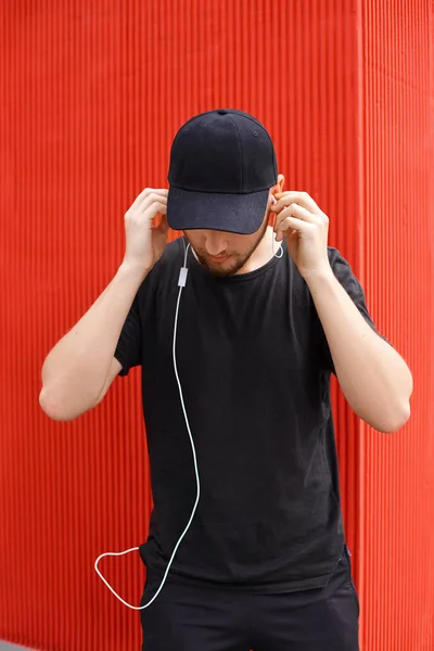 Beau mec avec une casquette noire et un t-shirt avec écouteurs — Photo